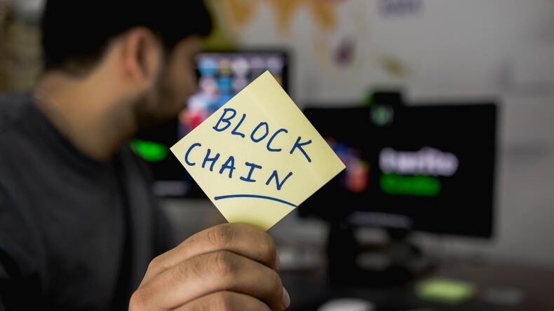 Man Showing a paper with writing 'Block chain'